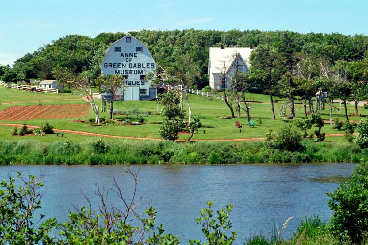 The Anne of Green Gables Museum and rural landscape in Prince Edward Island viewed across a body of water.