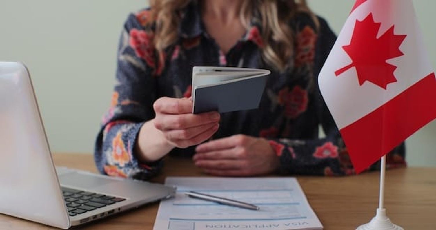woman holding passport with canada visa application form on desk