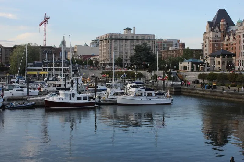 Boats docked in Victoria's Inner Harbour with downtown buildings and the Empress Hotel in the background.