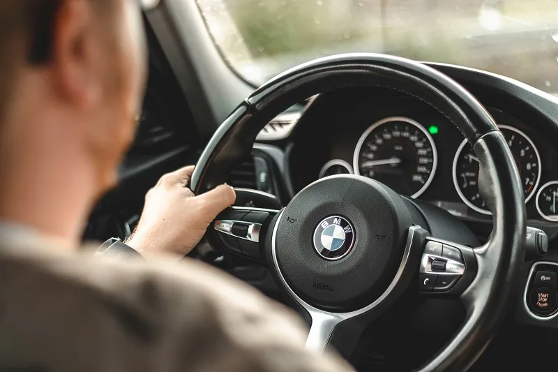 Driver’s hands on a BMW steering wheel, viewed from inside the car.