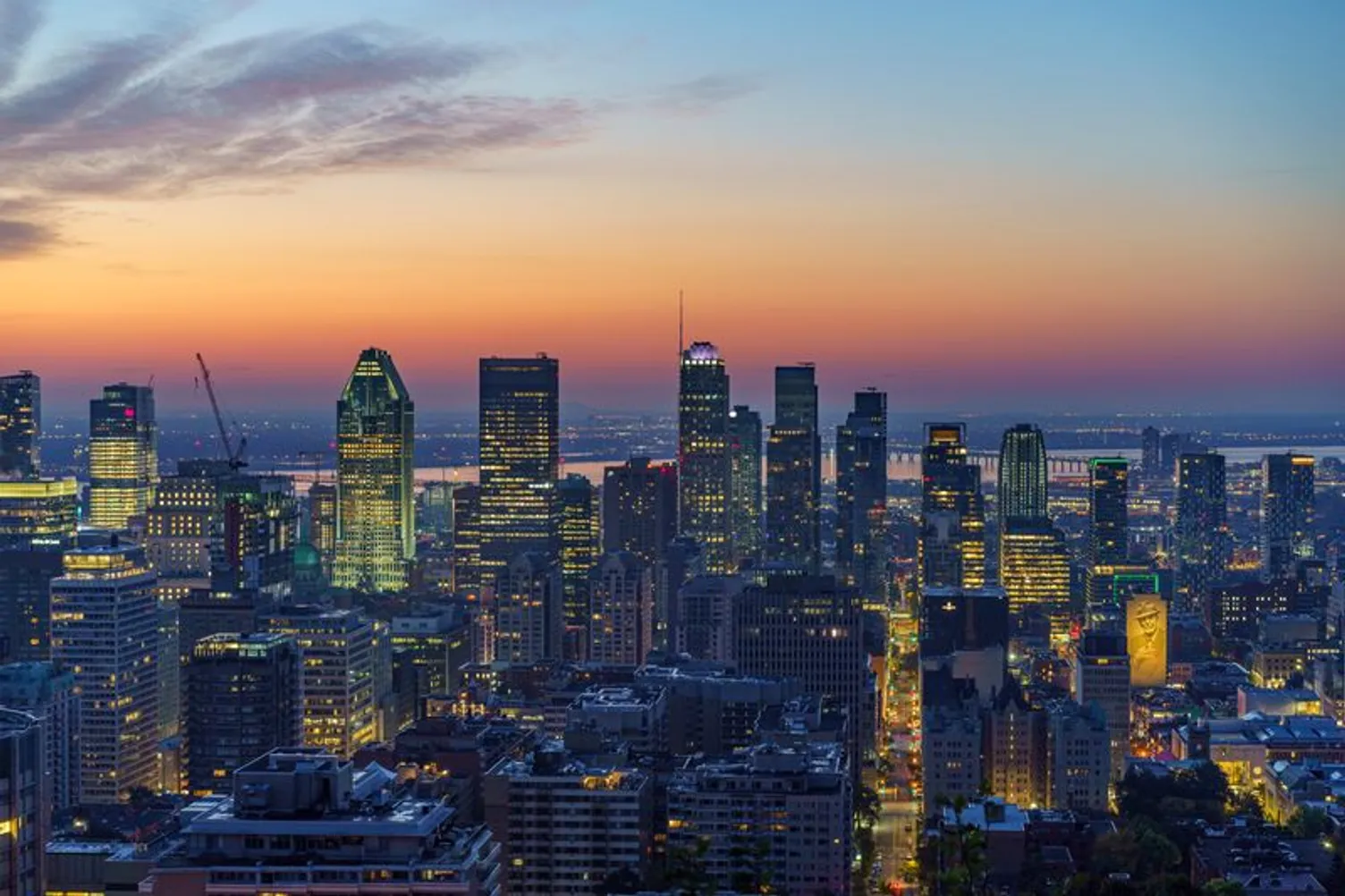 Aerial view of downtown Montreal's illuminated skyline at sunset.