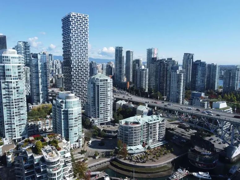 Aerial view of downtown Vancouver skyscrapers and a bridge along the waterfront on a clear day.