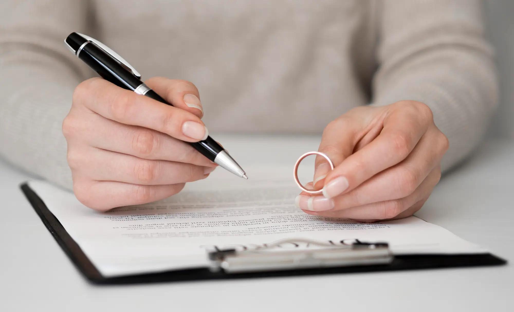 Hands holding a wedding ring and pen over a document – representing spousal sponsorship appeal process in Canada