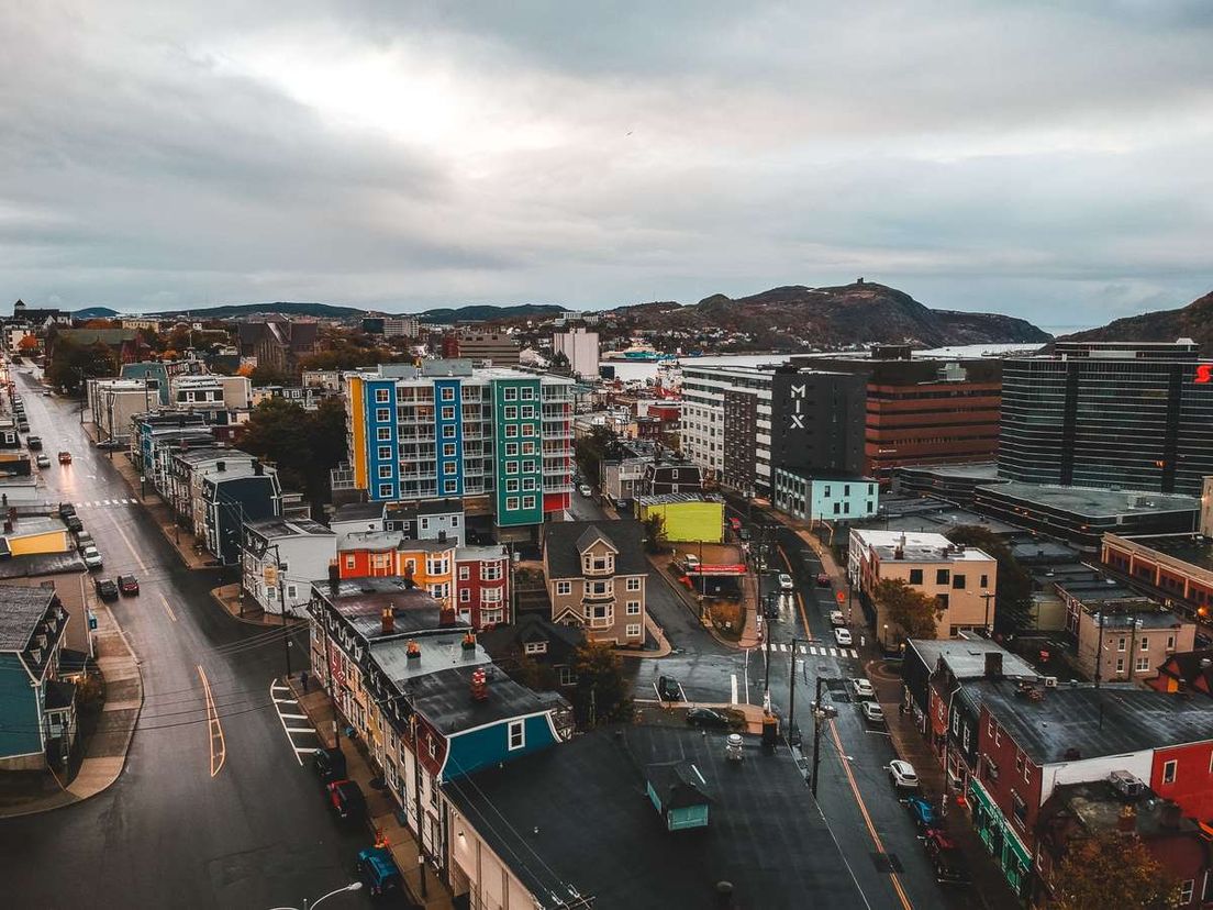 High-angle view of St. John's cityscape featuring colorful buildings, streets, and hills under an overcast sky.