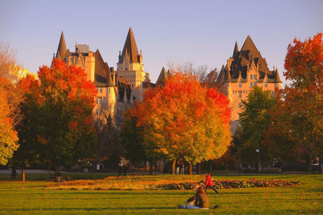 Chateau Laurier framed by vibrant autumn trees and a grassy lawn in Ottawa, Ontario.