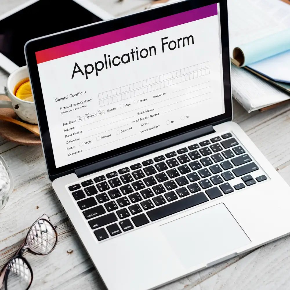 submitting visa application form with documents and laptop on desk