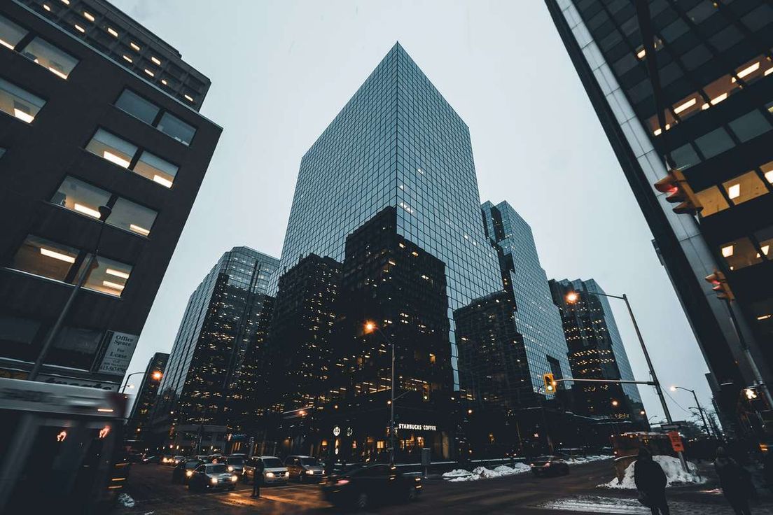 Low-angle view of modern glass skyscrapers above a city street on a winter evening.