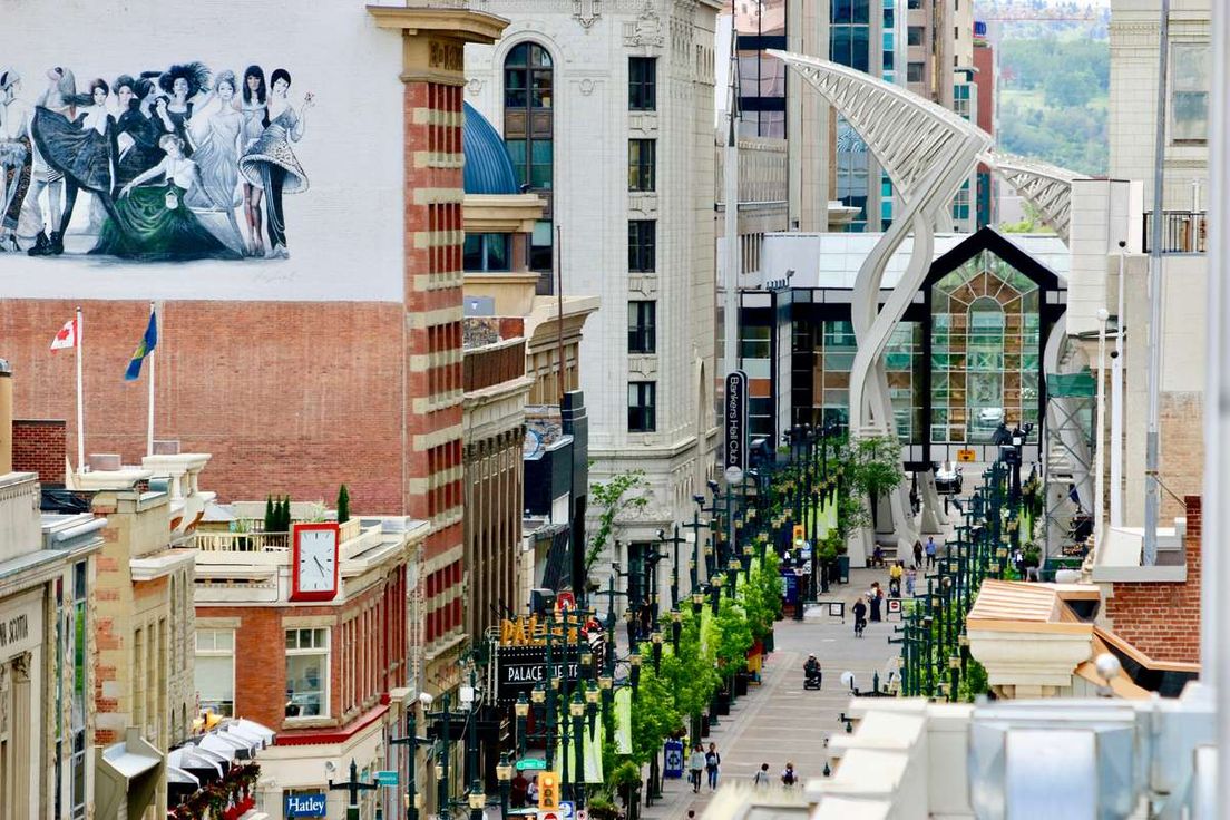 Elevated view of Stephen Avenue pedestrian mall in downtown Calgary with historic buildings and white steel arches.