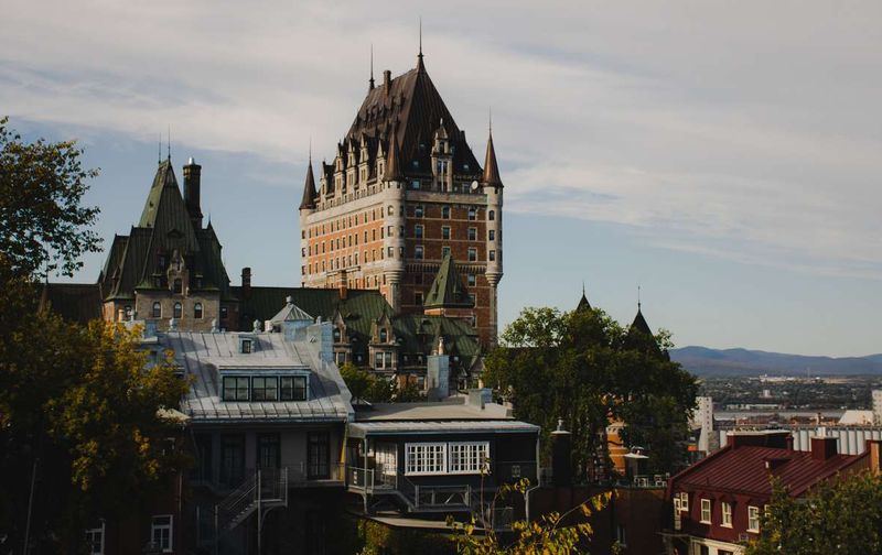 The historic Château Frontenac hotel towering over Old Quebec City under a partly cloudy sky.