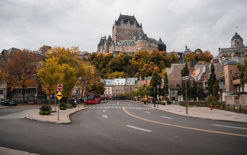 A street in Old Quebec City with autumn trees and the historic Château Frontenac hotel on the hill.