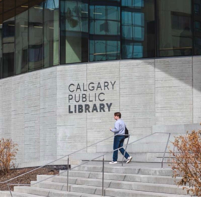 A person walks up the steps outside the Calgary Public Library building.