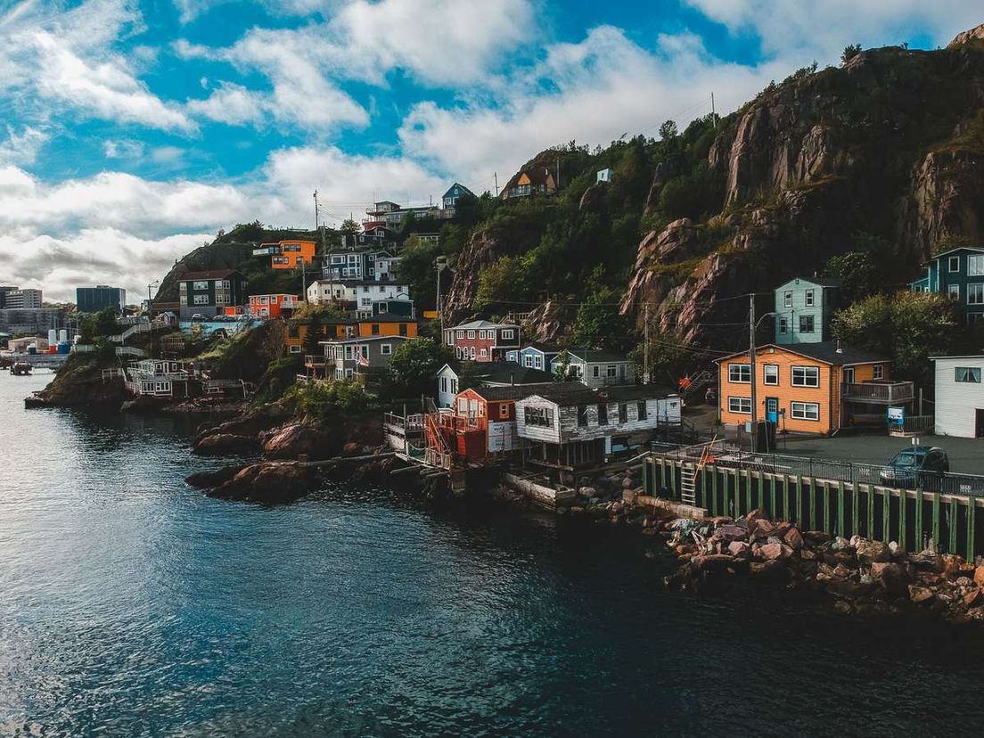Colorful houses built on a rocky hillside along the water in Newfoundland.