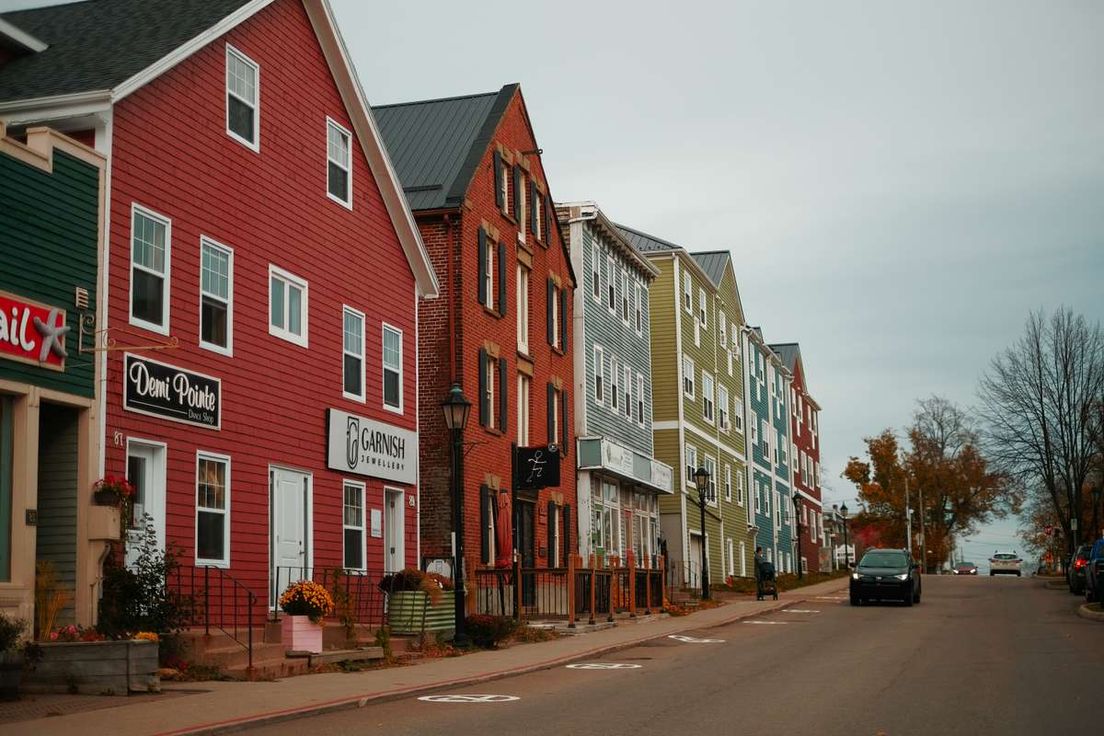 A row of colorful multi-story buildings and small shops along a quiet street on an overcast day.