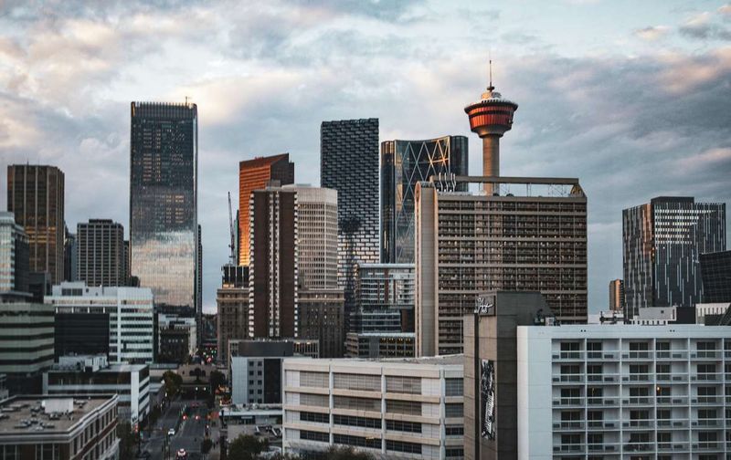 Downtown Calgary skyline featuring tall skyscrapers and the Calgary Tower under a cloudy sky.