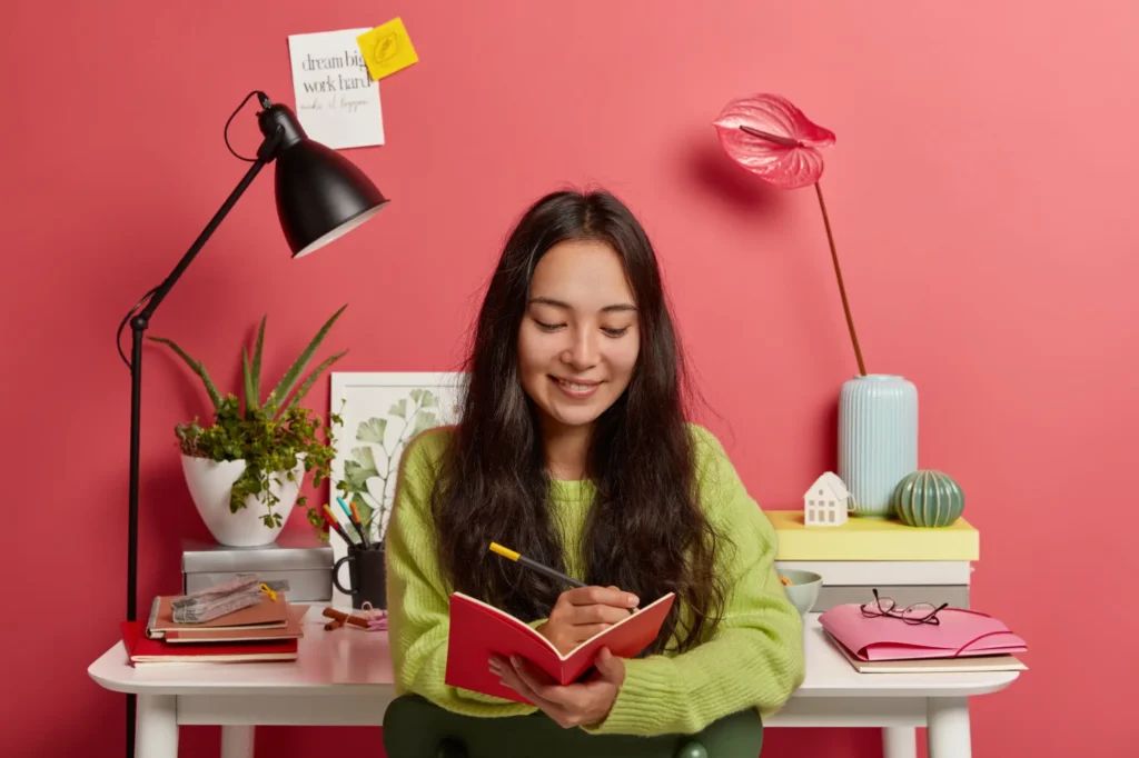 Self-employed woman writing in notebook at home office for Canada self-employed immigration program
