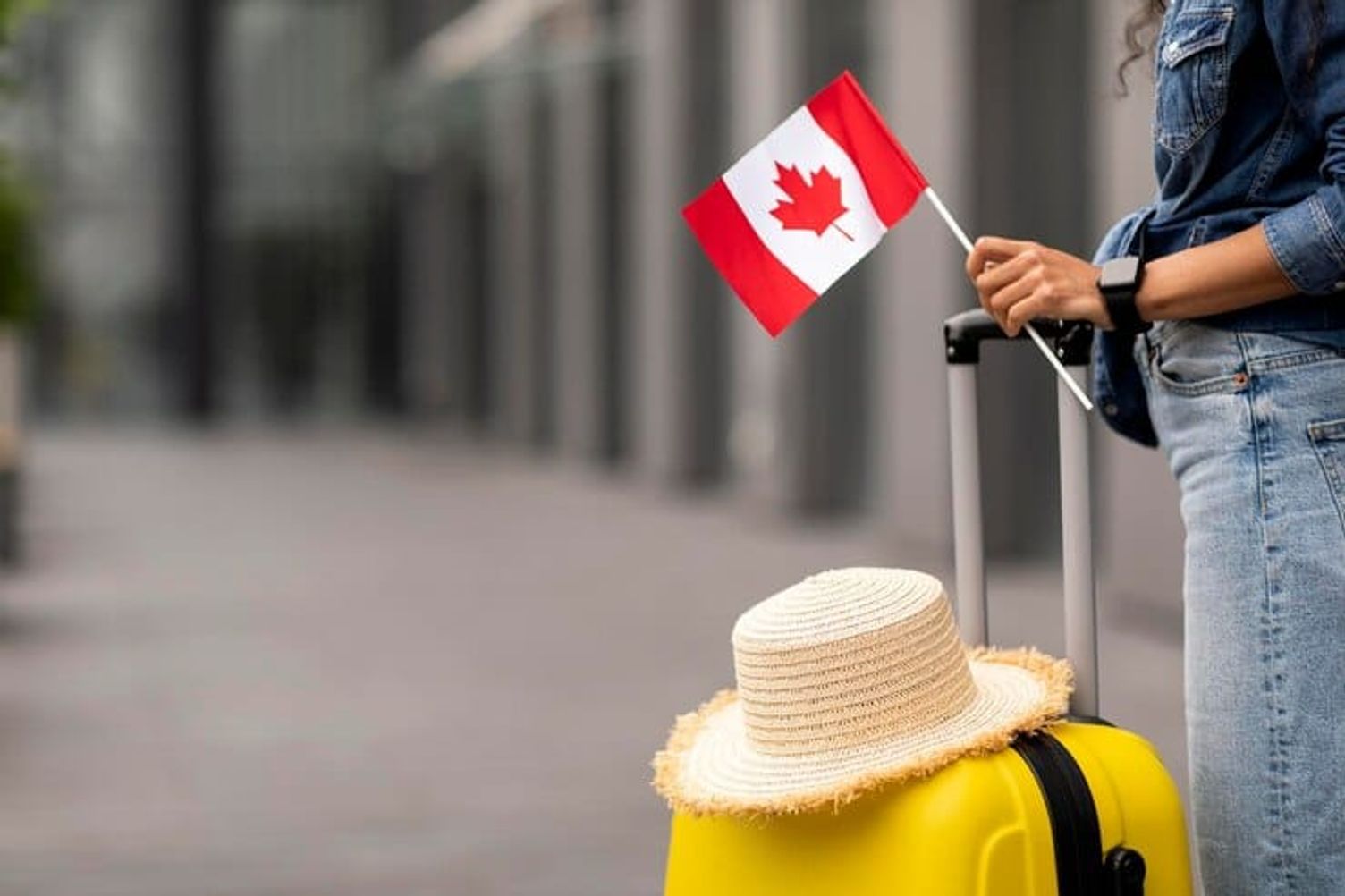 woman with suitcase holding canada flag arriving as newcomer