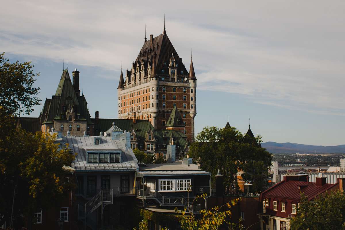 The historic Château Frontenac hotel towering over Old Quebec City under a partly cloudy sky.