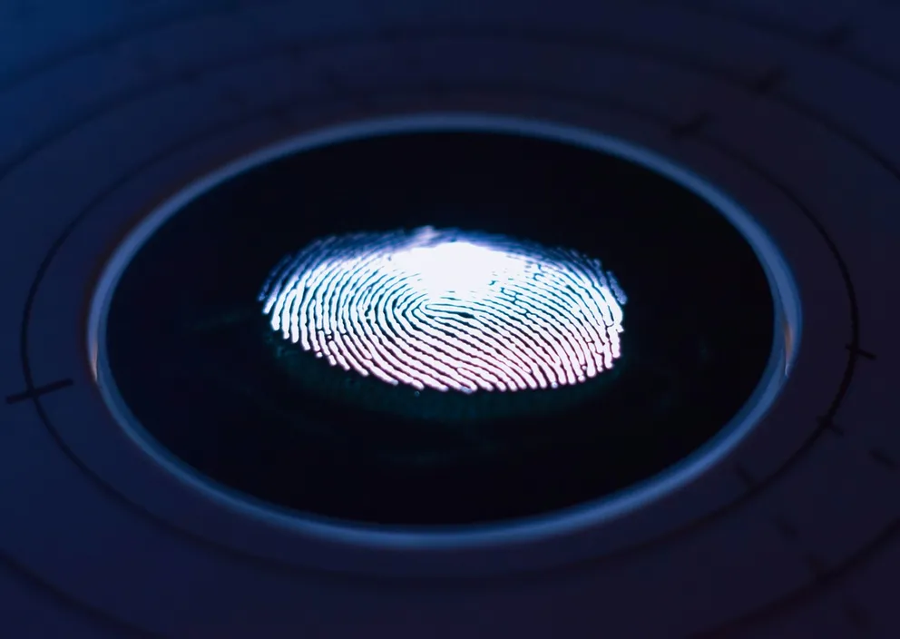 A glowing fingerprint scan illuminated on a dark circular biometric scanner.