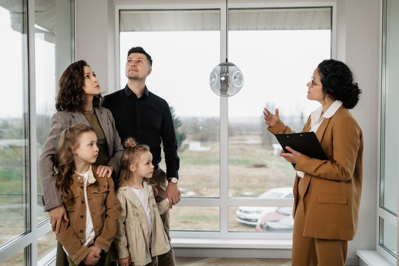 A real estate agent with a clipboard shows an apartment to a family of four.