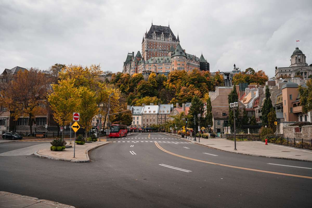 A street in Old Quebec City with autumn trees and the historic Château Frontenac hotel on the hill.