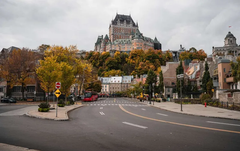 A street in Old Quebec City with autumn trees and the historic Château Frontenac hotel on the hill.