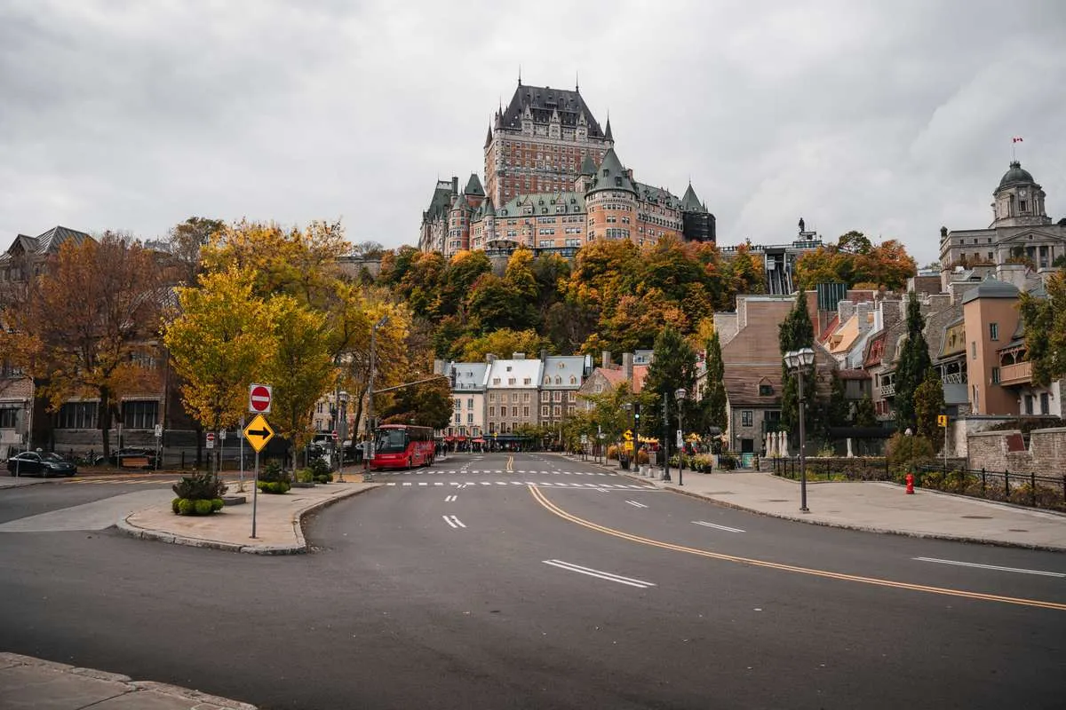 A street in Old Quebec City with autumn trees and the historic Château Frontenac hotel on the hill.
