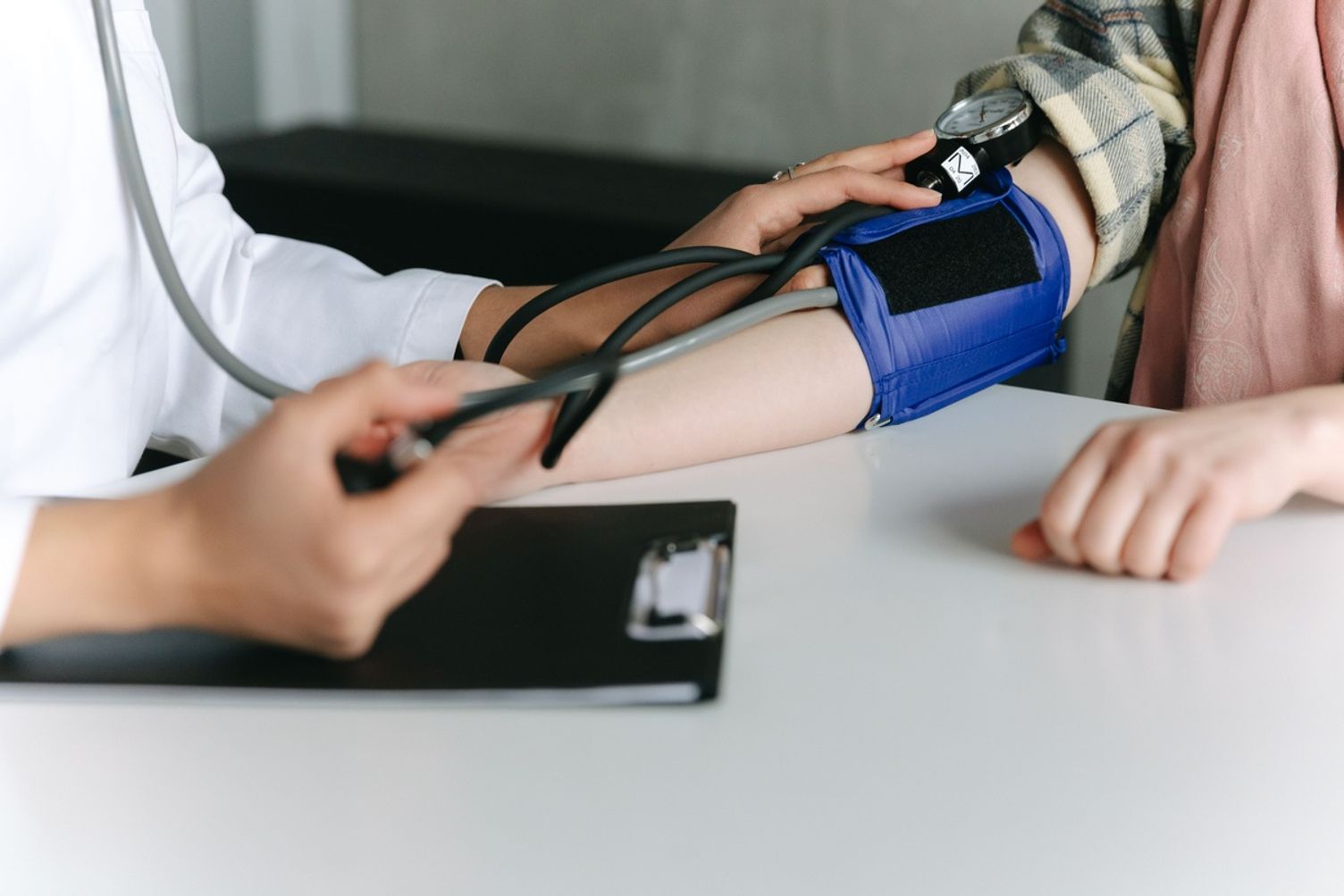 A healthcare provider measuring a patient's blood pressure with a manual cuff.