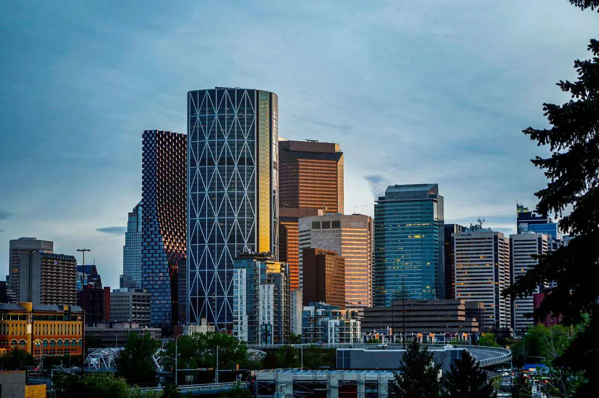 Modern downtown Calgary skyline featuring tall glass skyscrapers under a blue sky.