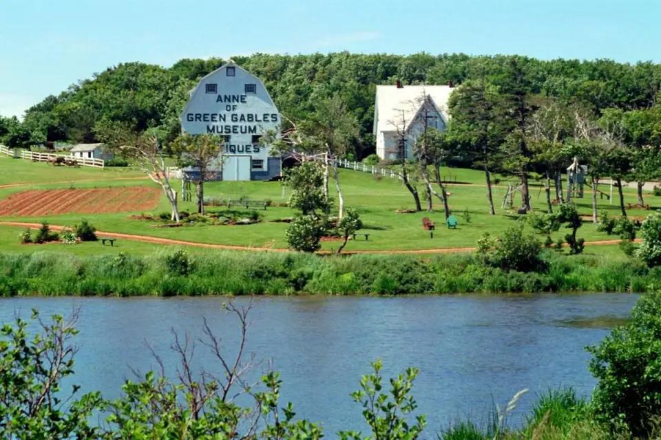 The Anne of Green Gables Museum and rural landscape in Prince Edward Island viewed across a body of water.