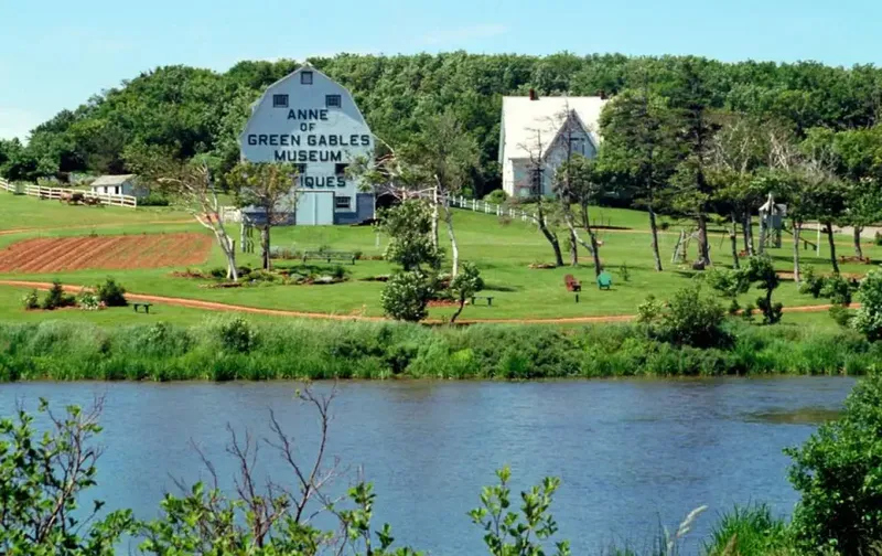 The Anne of Green Gables Museum and rural landscape in Prince Edward Island viewed across a body of water.