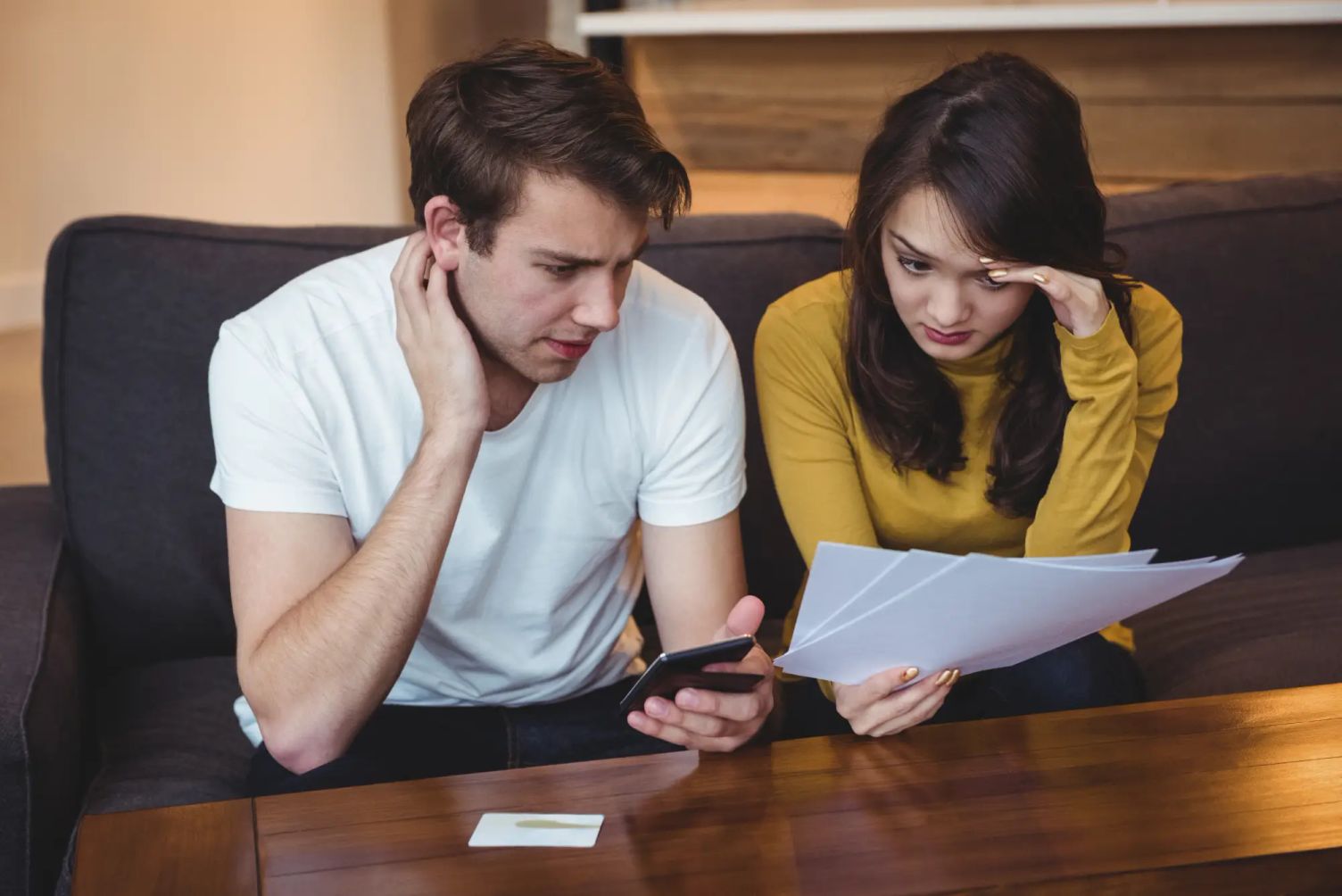A couple reviewing documents and phone messages to avoid fraud in Canada