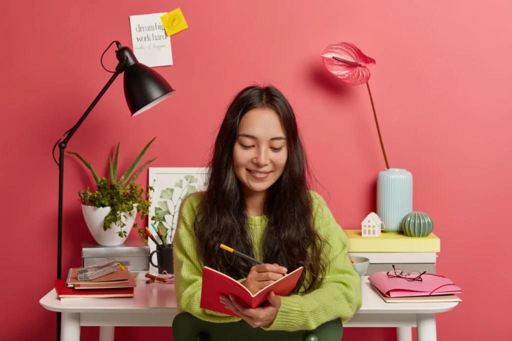 Self-employed woman writing in notebook at home office for Canada self-employed immigration program