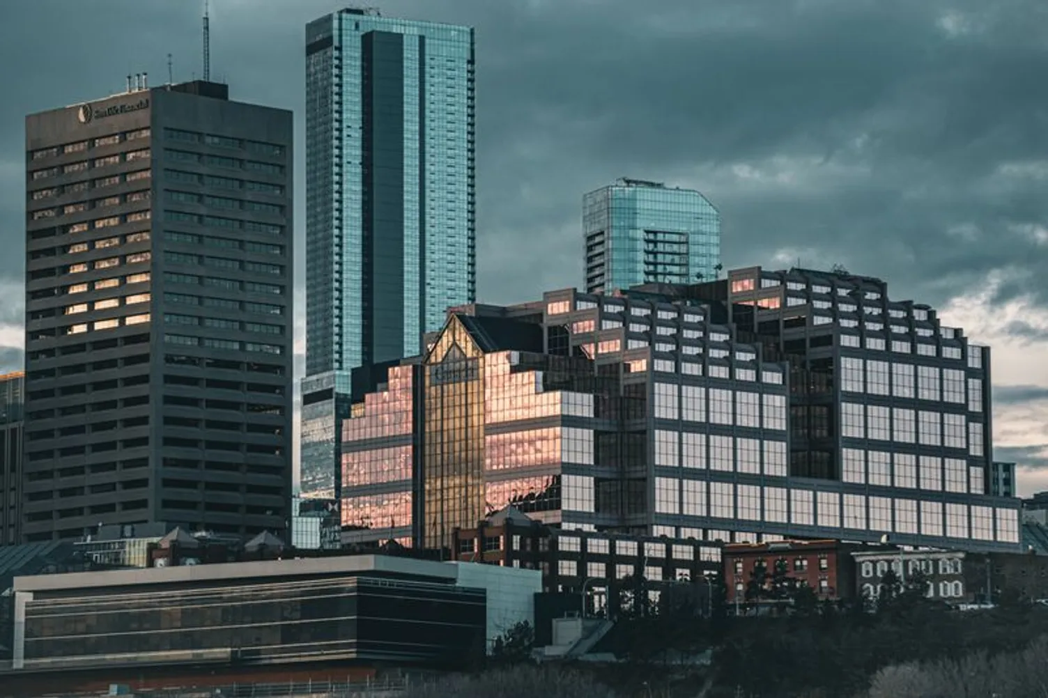Modern high-rise office towers and skyscrapers in downtown Edmonton under a cloudy sky.