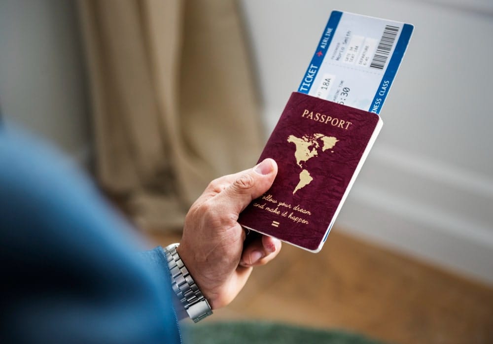 Person holding a pen and filling out a form on a clipboard, with a passport