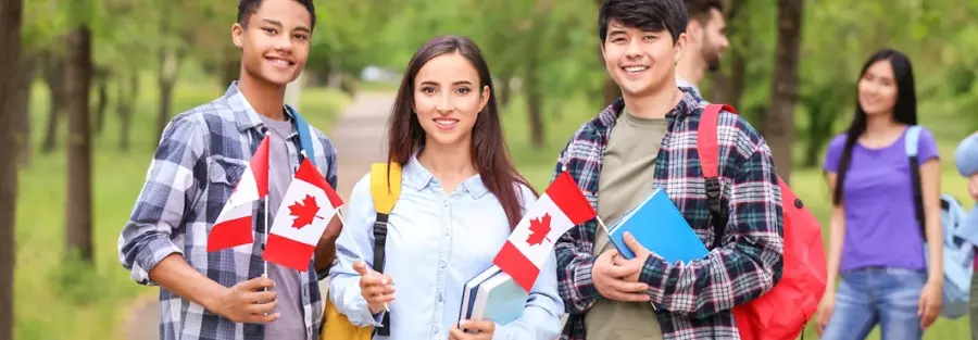 three Canadian students standing side by side and each holding a Canadian flag