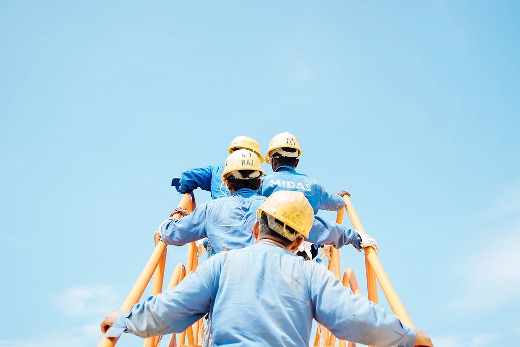 four construction workers climbing stairs with a blue sky in the backgroud