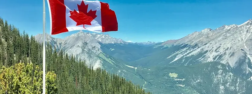 a picture of the Canadian flag on a hill with the blue sky in the background