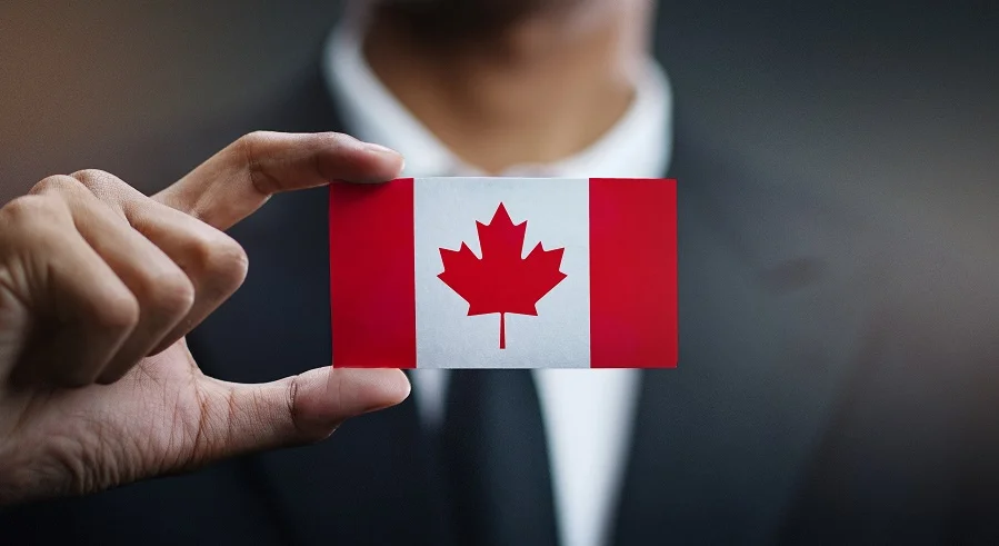 a man in a suit holding up a badge with the Canadian flag on it