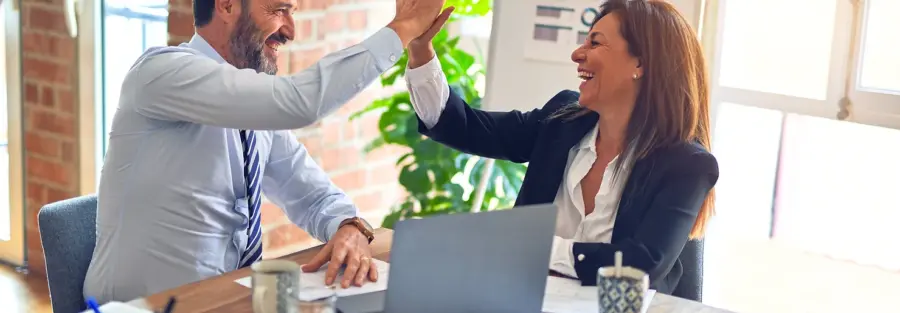 a middle-aged lady and man high-fiving behind a desk