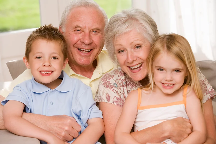 A family consisting of two parents and two children sitting next to each other happily