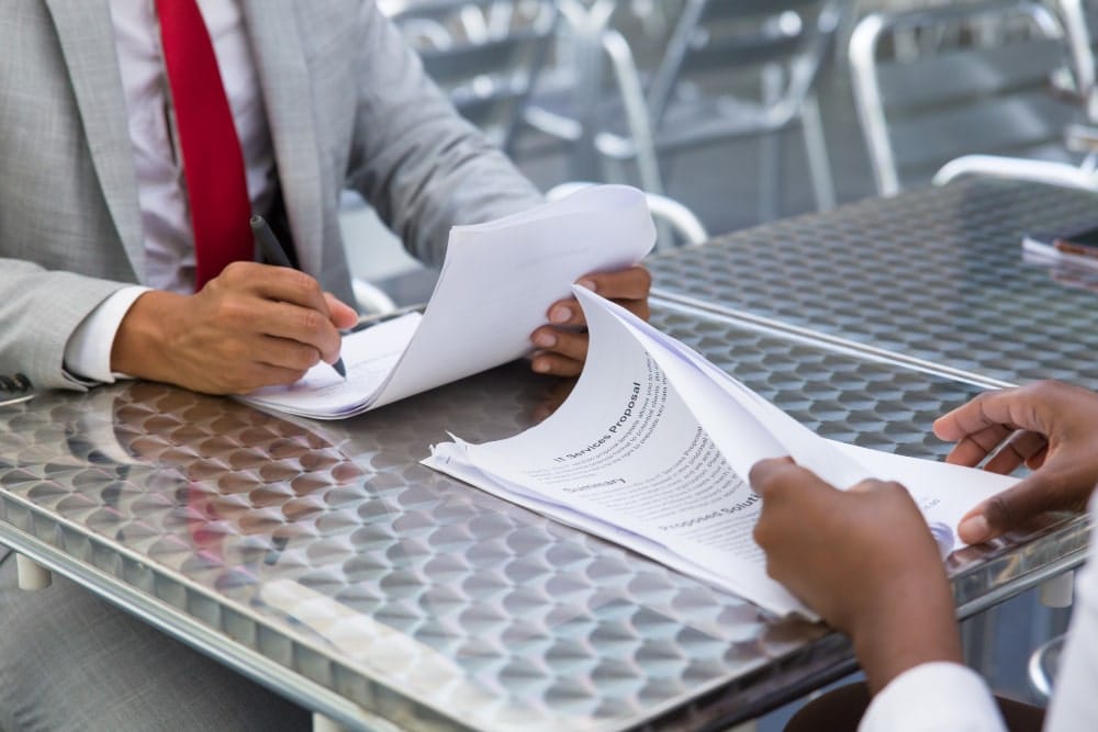 Signing documents at a metal table.