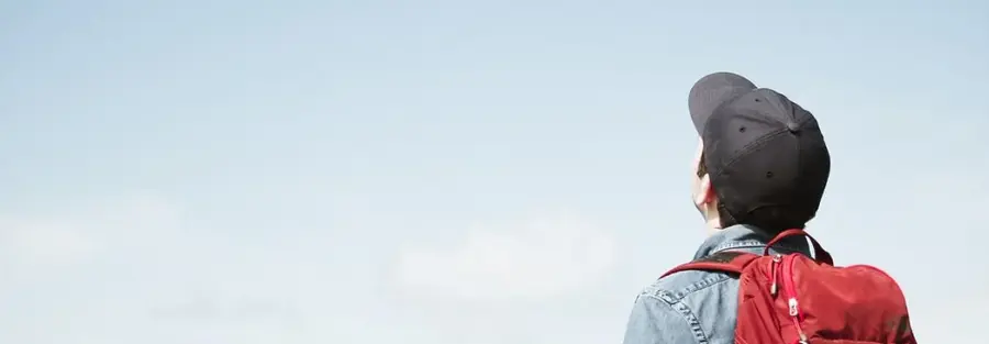 a student with a backpack on, staring at the blue sky