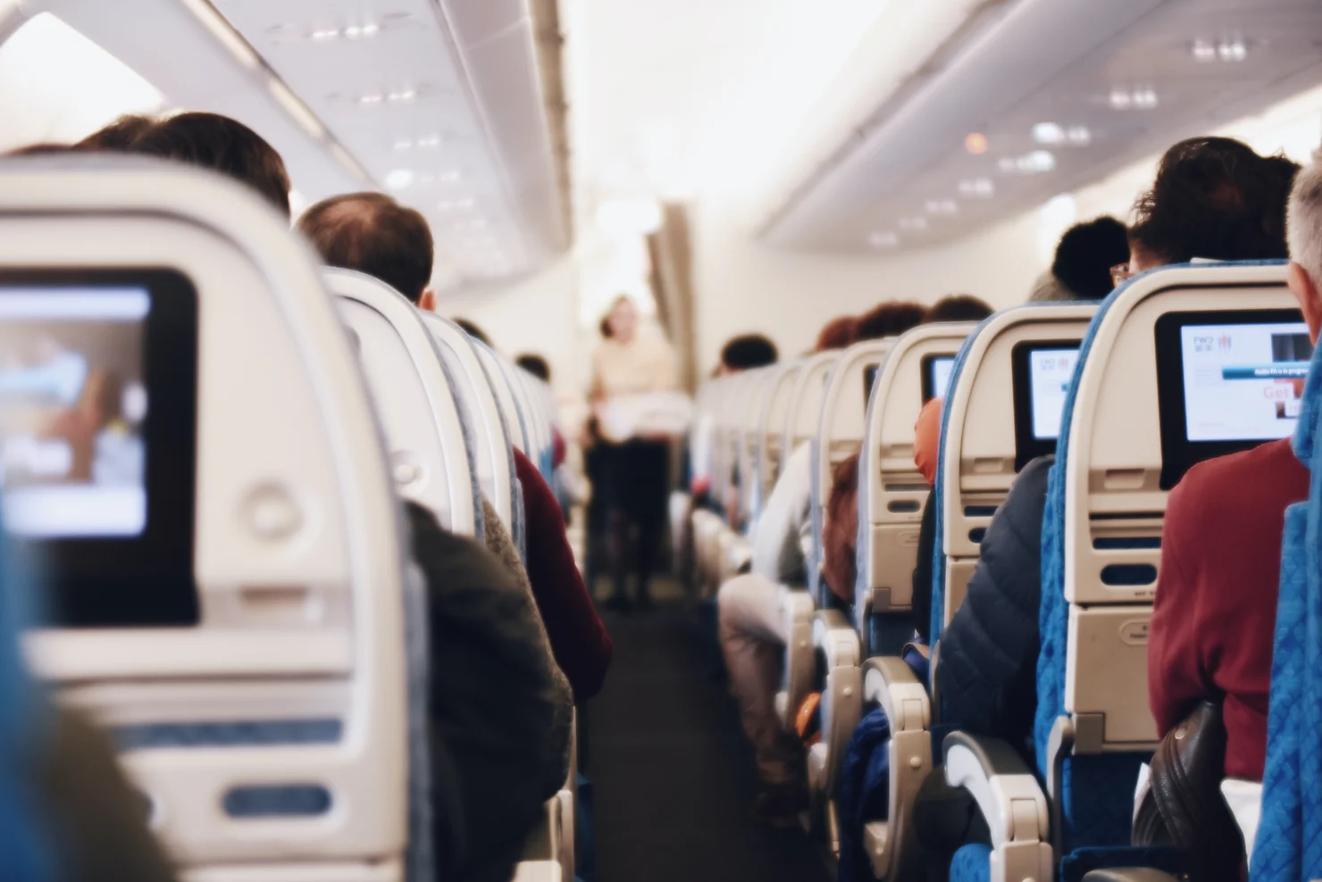 the middle line of an airplane with people watching programs on the screen