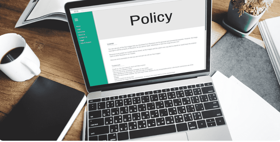 The laptop screen shows a policy.
