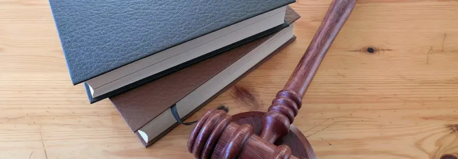 A wooden gavel and two notebooks on a wooden table