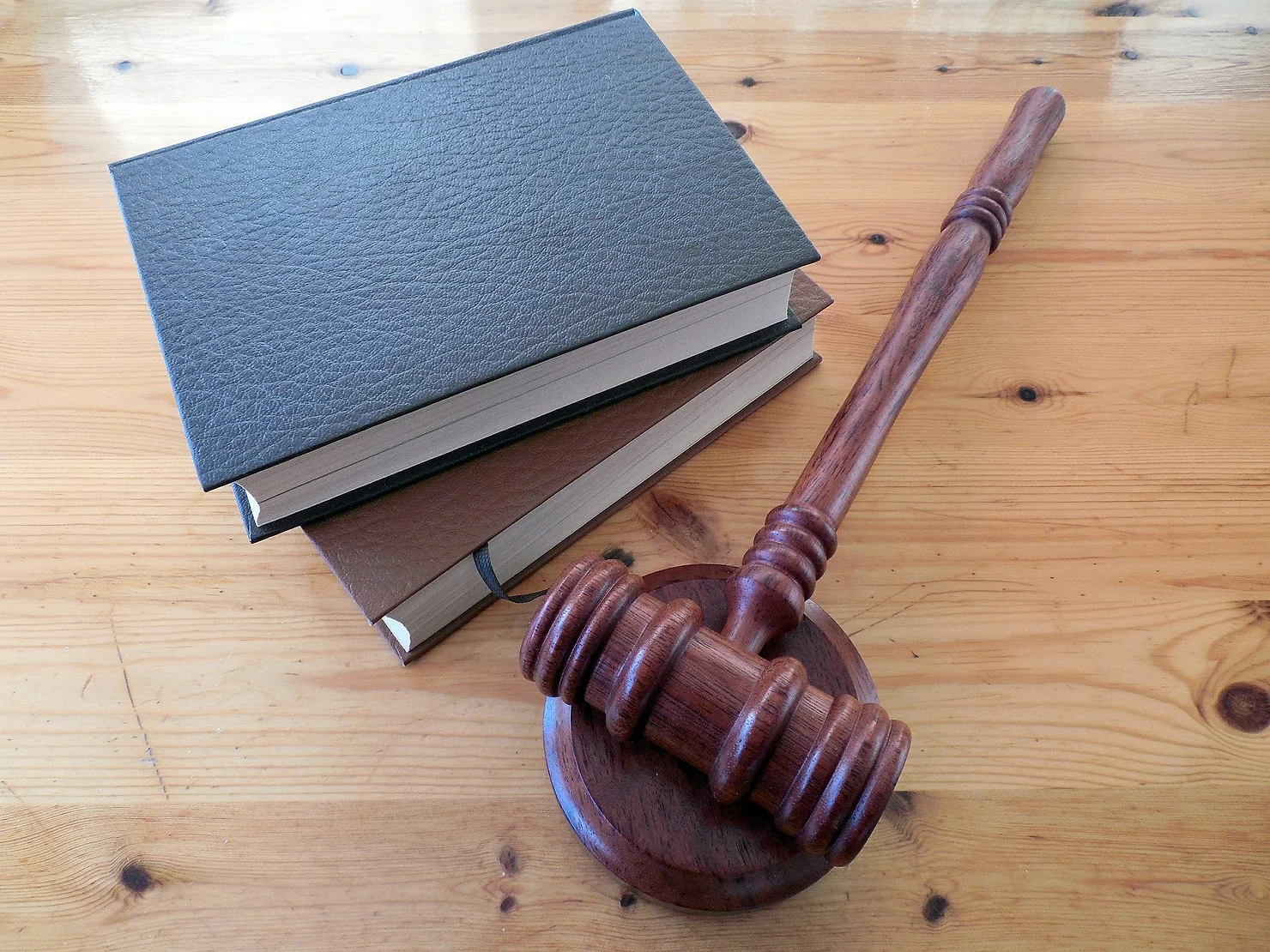 A wooden gavel and two notebooks on a wooden table