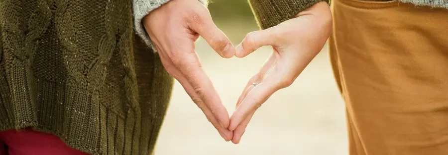 two people holding hands in a way that forms the shape of a heart