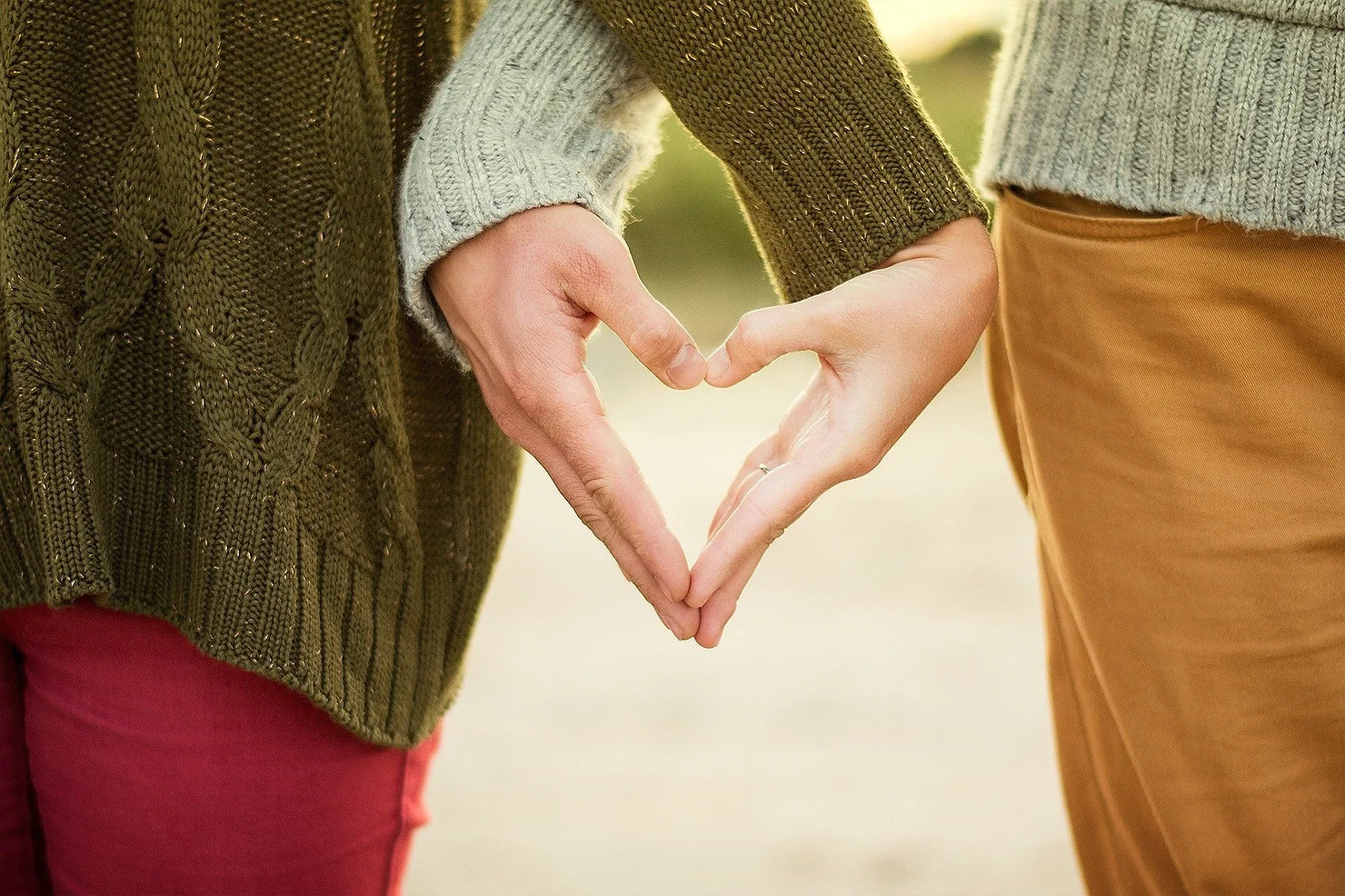 two people holding hands in a way that forms the shape of a heart