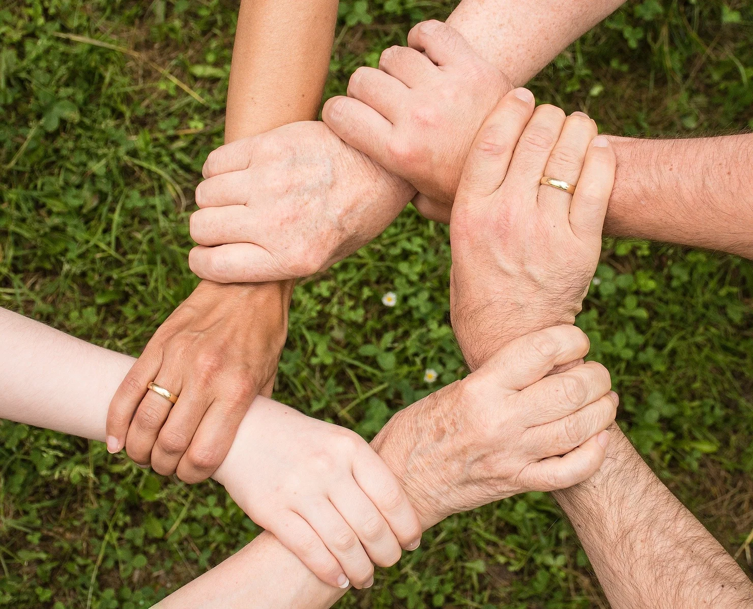 six people holding each other's wrist in a way that forms a hexagon