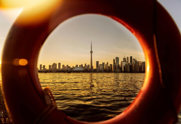 view of a toronto skyline at sunset framed through a lifebuoy ring